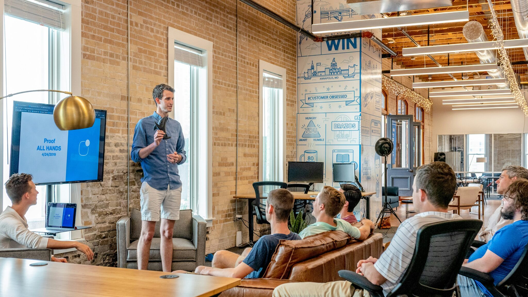 standing man speaking to a seated group in an industrial office