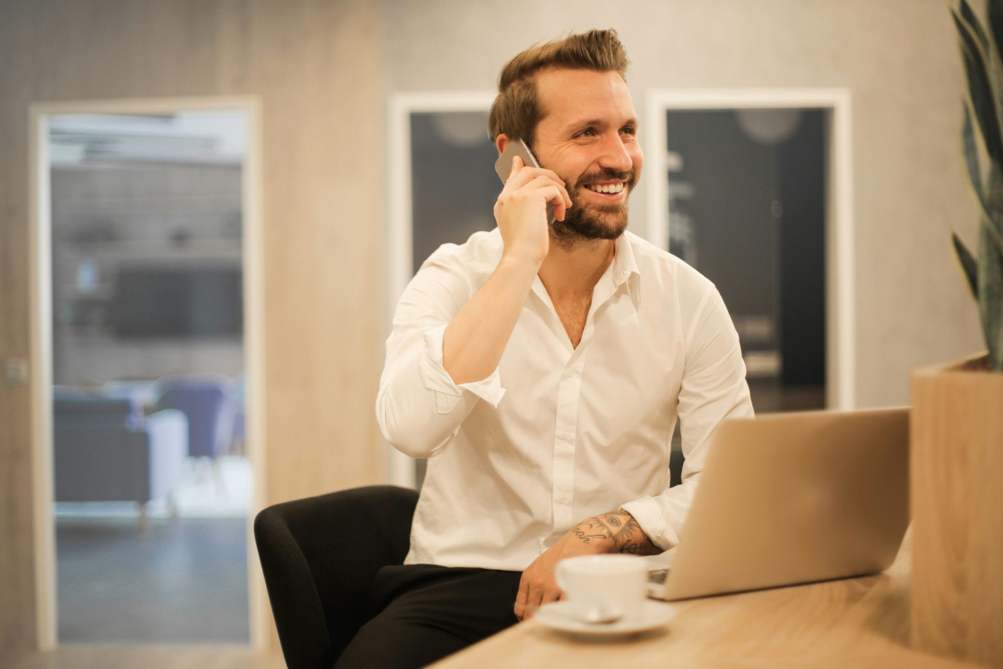 man with laptop and coffee talking on mobile phone