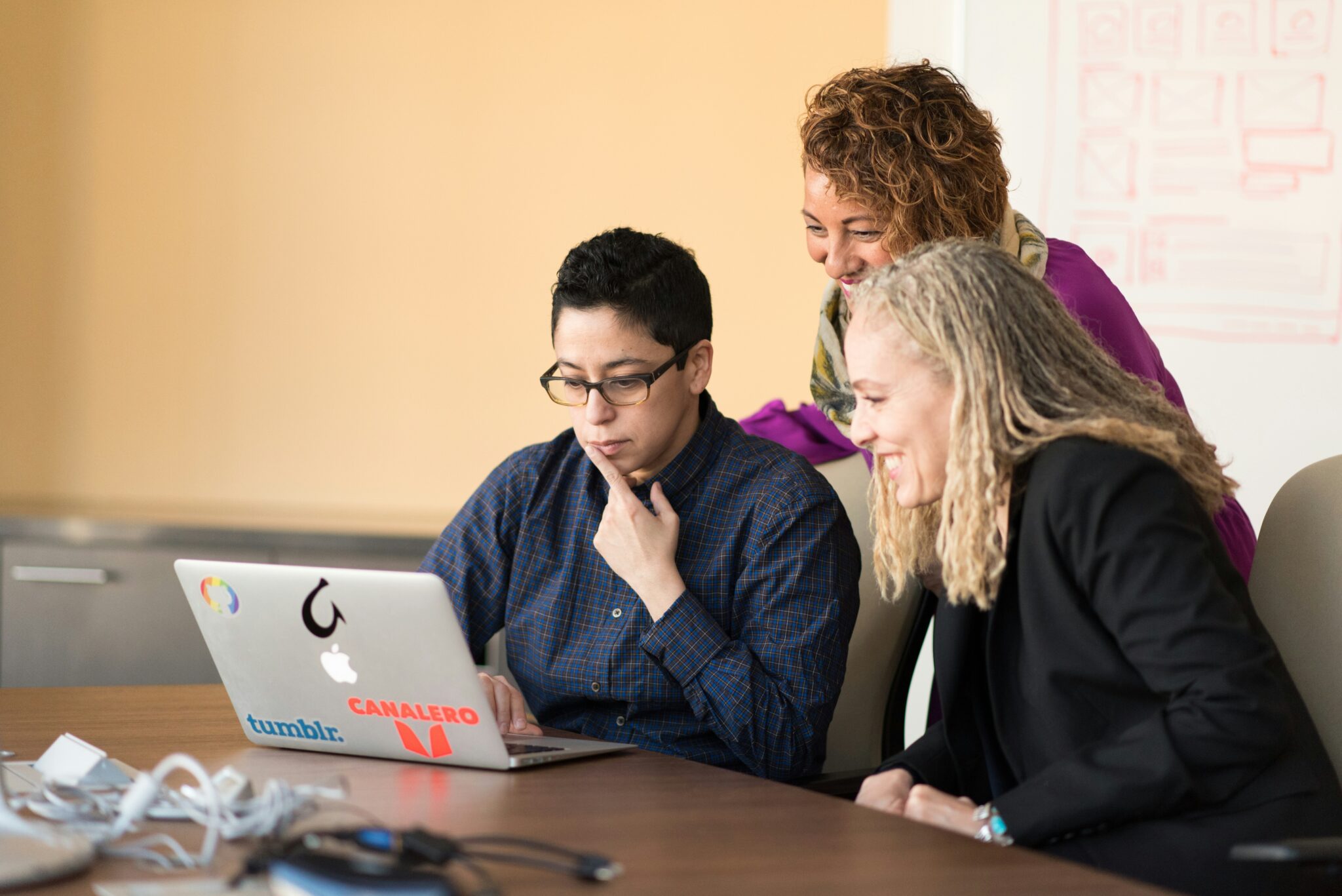 three people smiling with a laptop