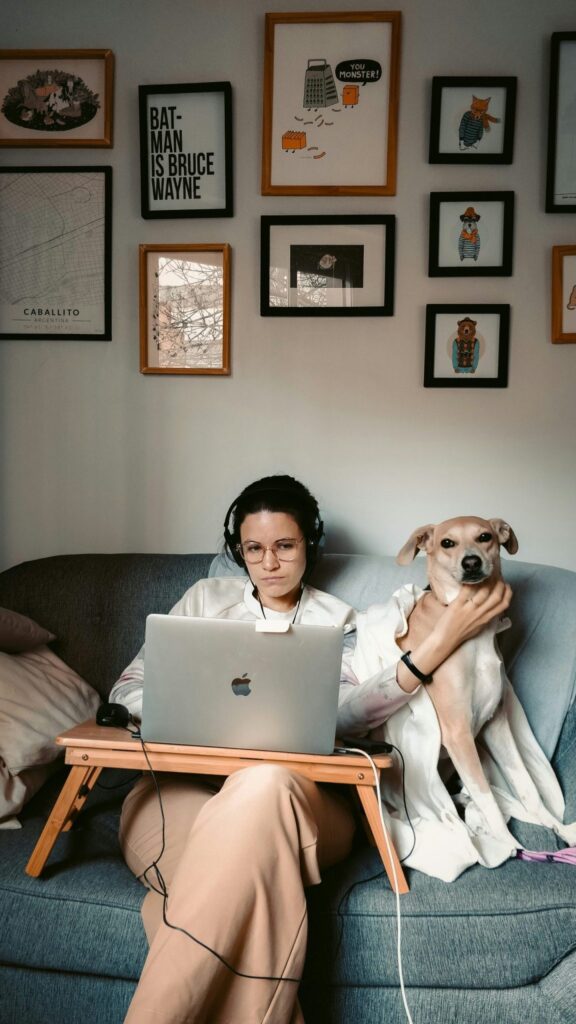 woman and dog sitting on a couch working