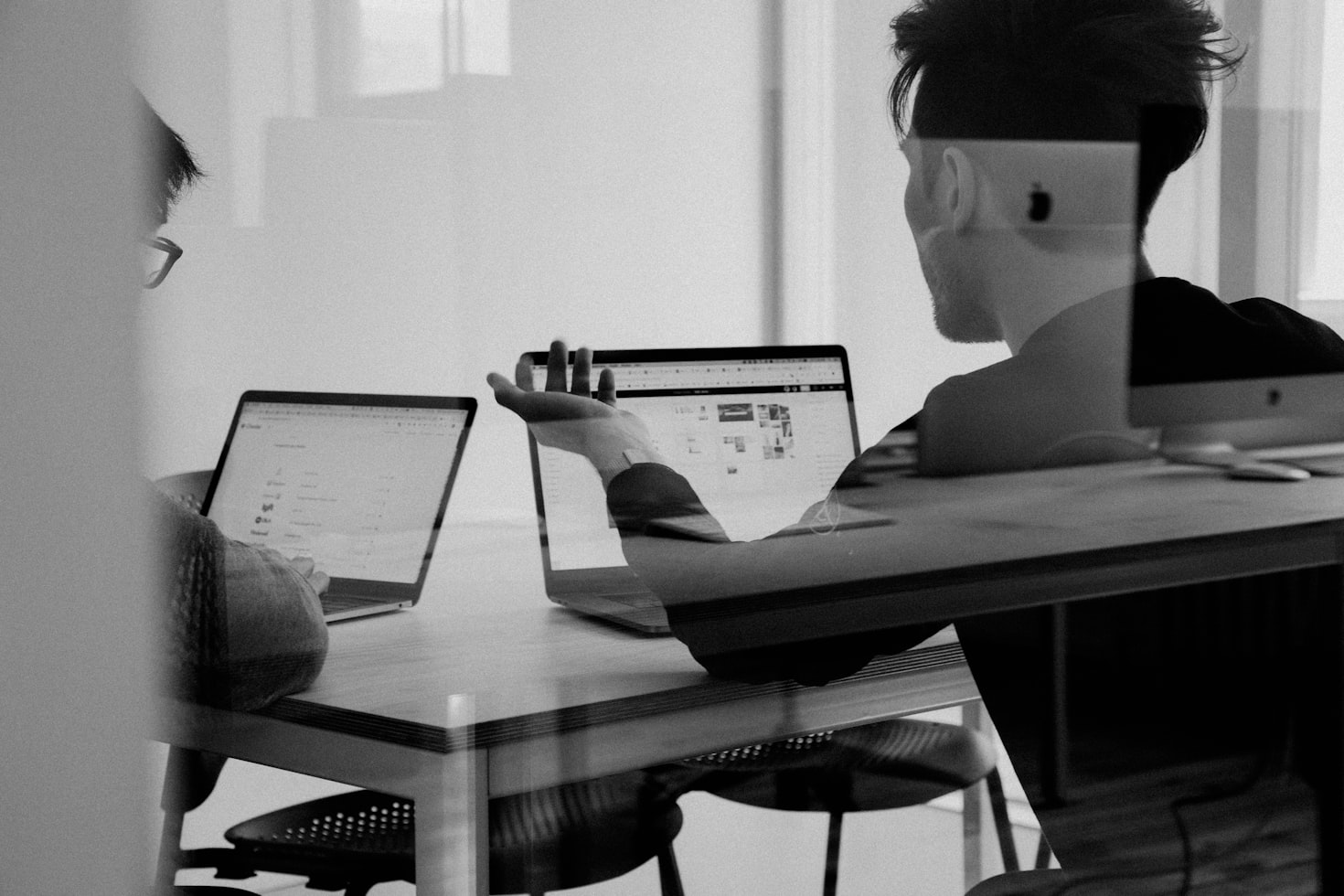 black and white image of two men talking at laptops