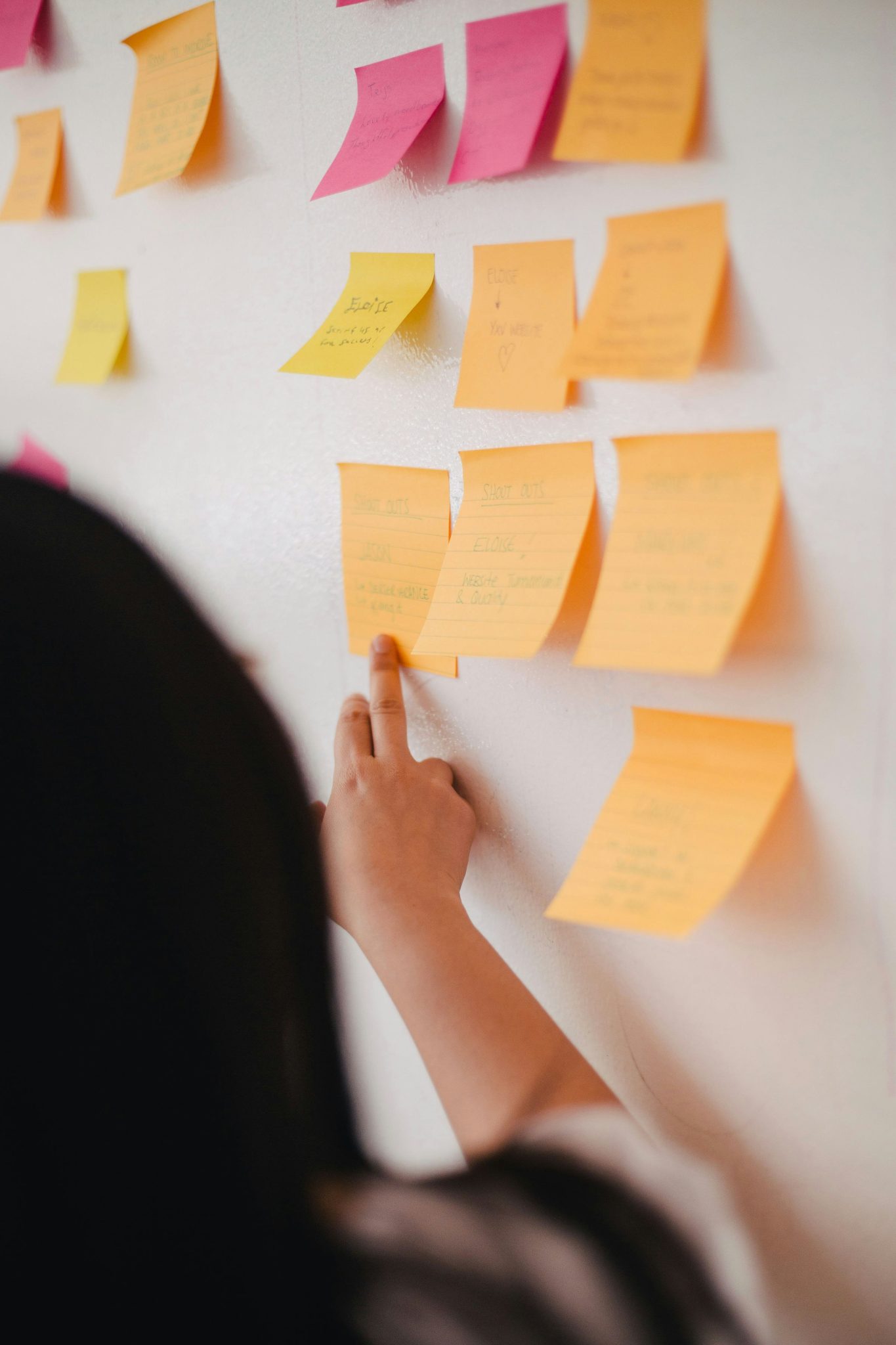 person pointing at orange sticky notes