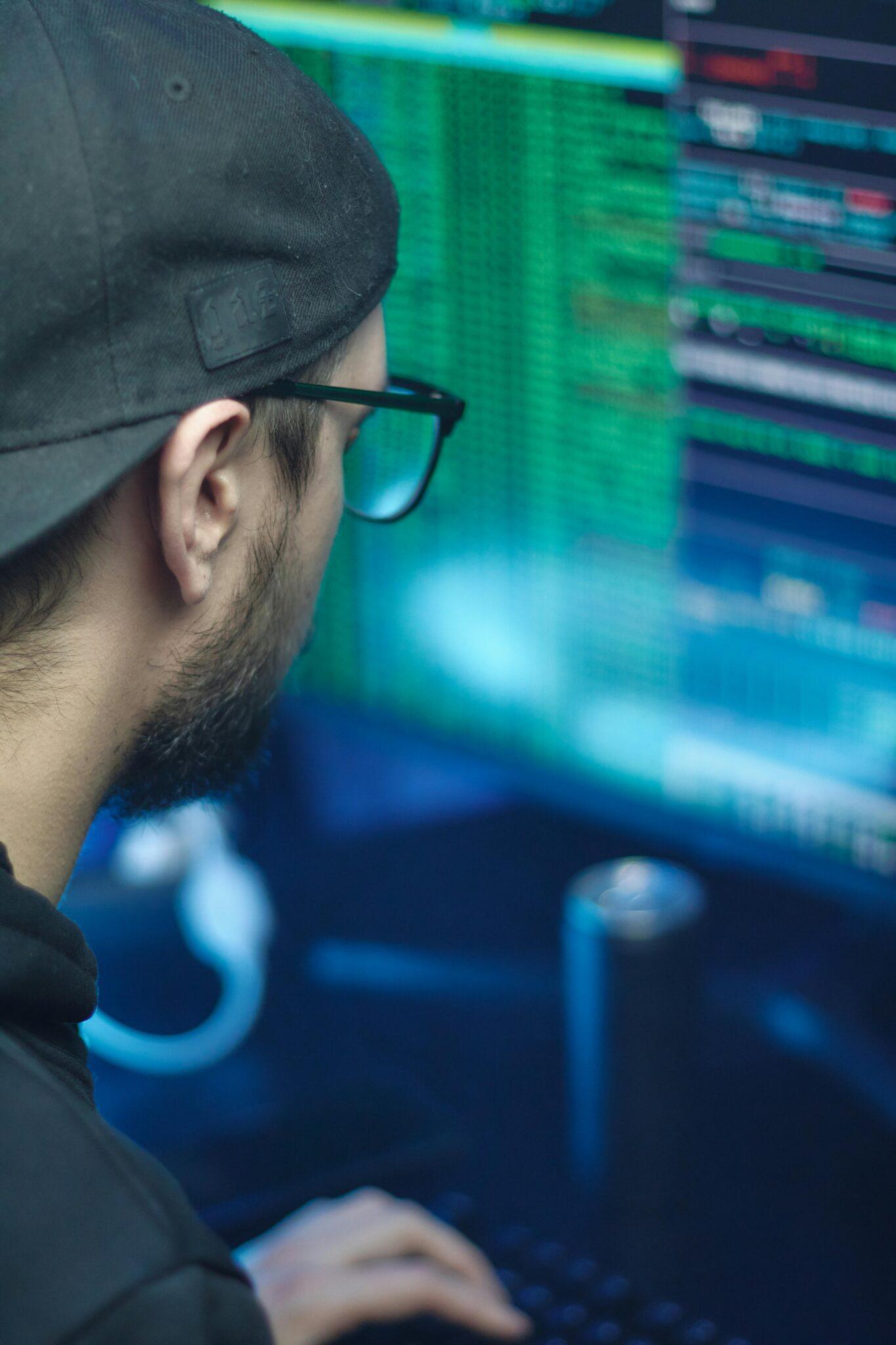 man looking at a monitor with rows of green text