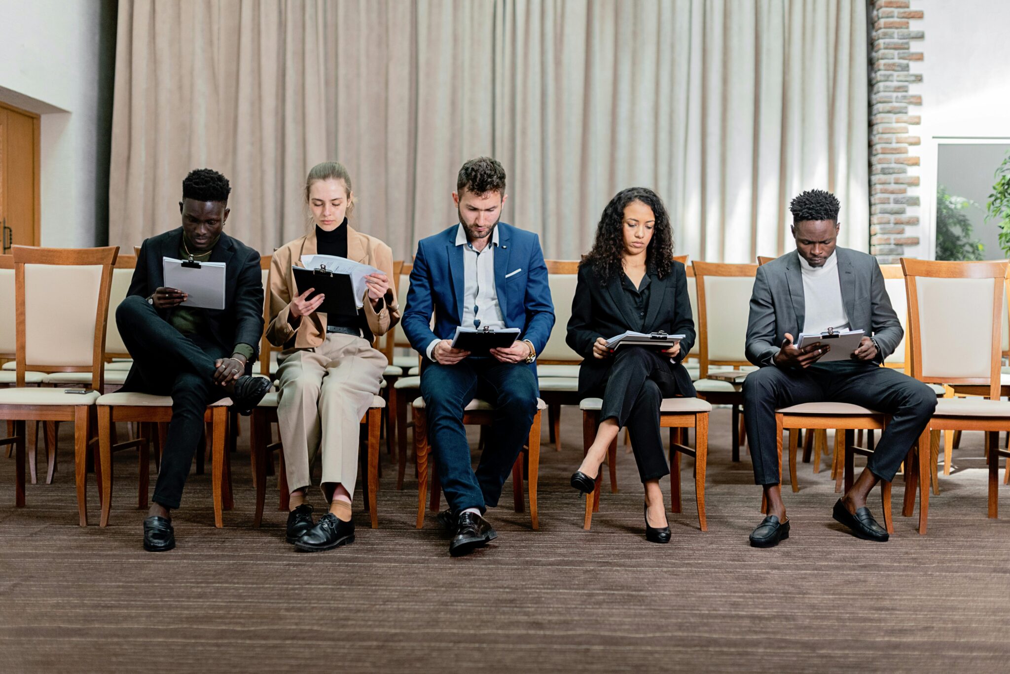 five people sitting in chairs reading documents