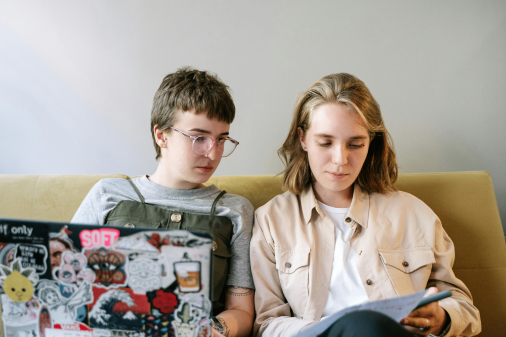 two people sitting on a yellow couch reading
