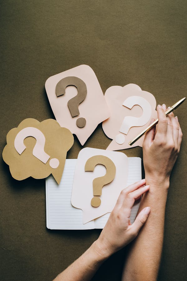 hands with four question mark paper cutouts