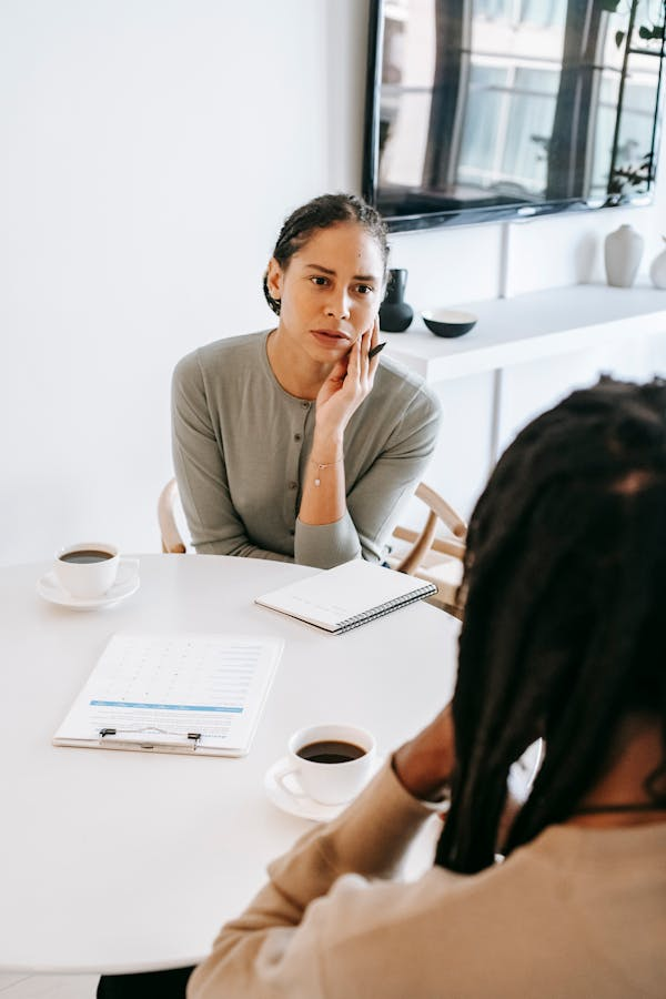 two people sit at a round table with coffee and a clipboard