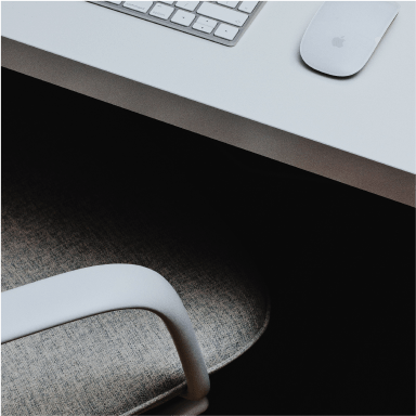 empty desk chair at a white desk with mouse and keyboard