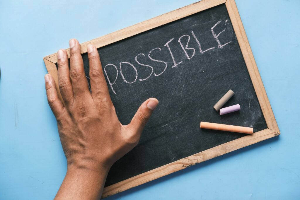 hand on chalkboard showing chalk and the world Possible