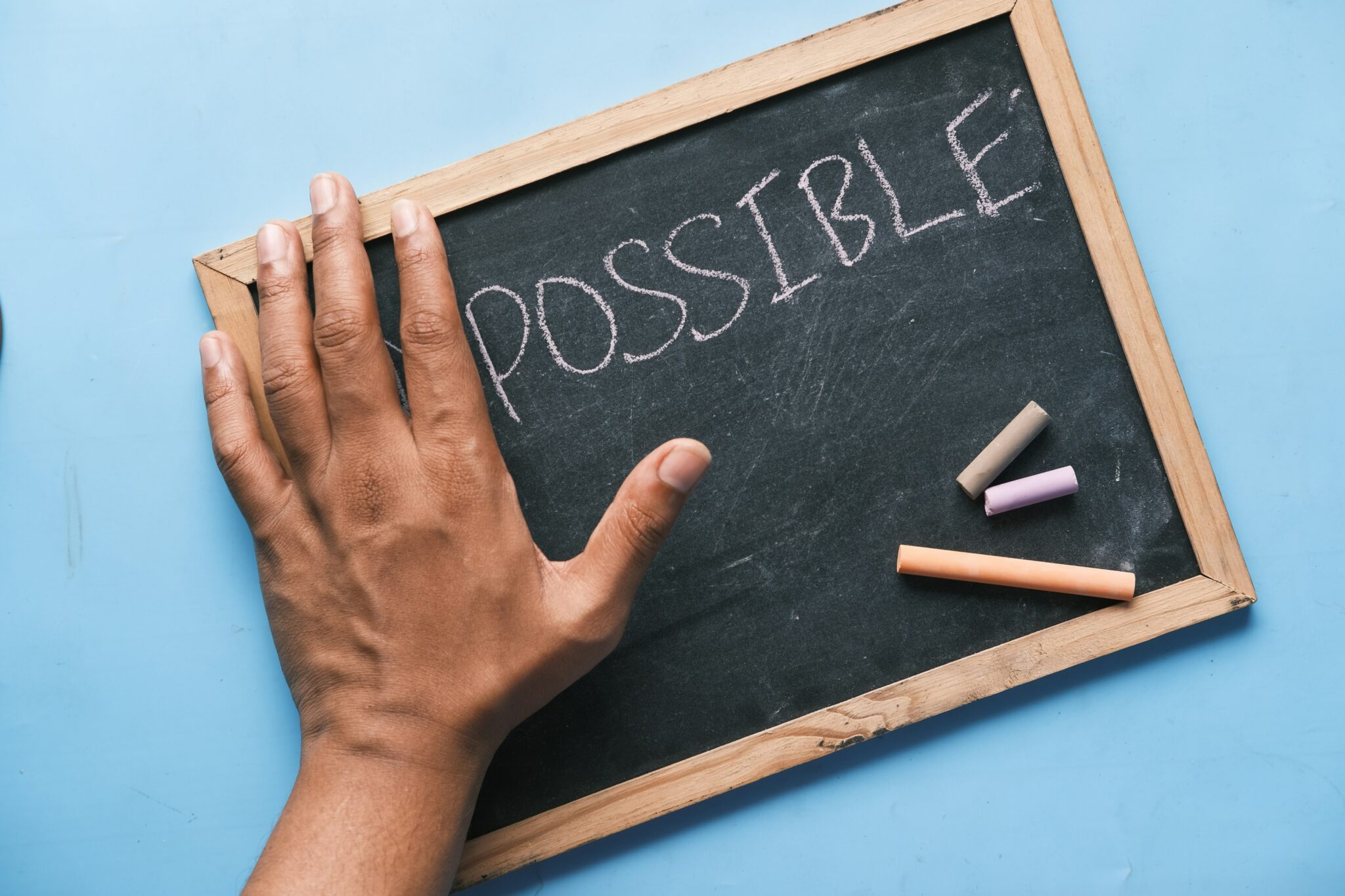 hand on chalkboard showing chalk and the world Possible
